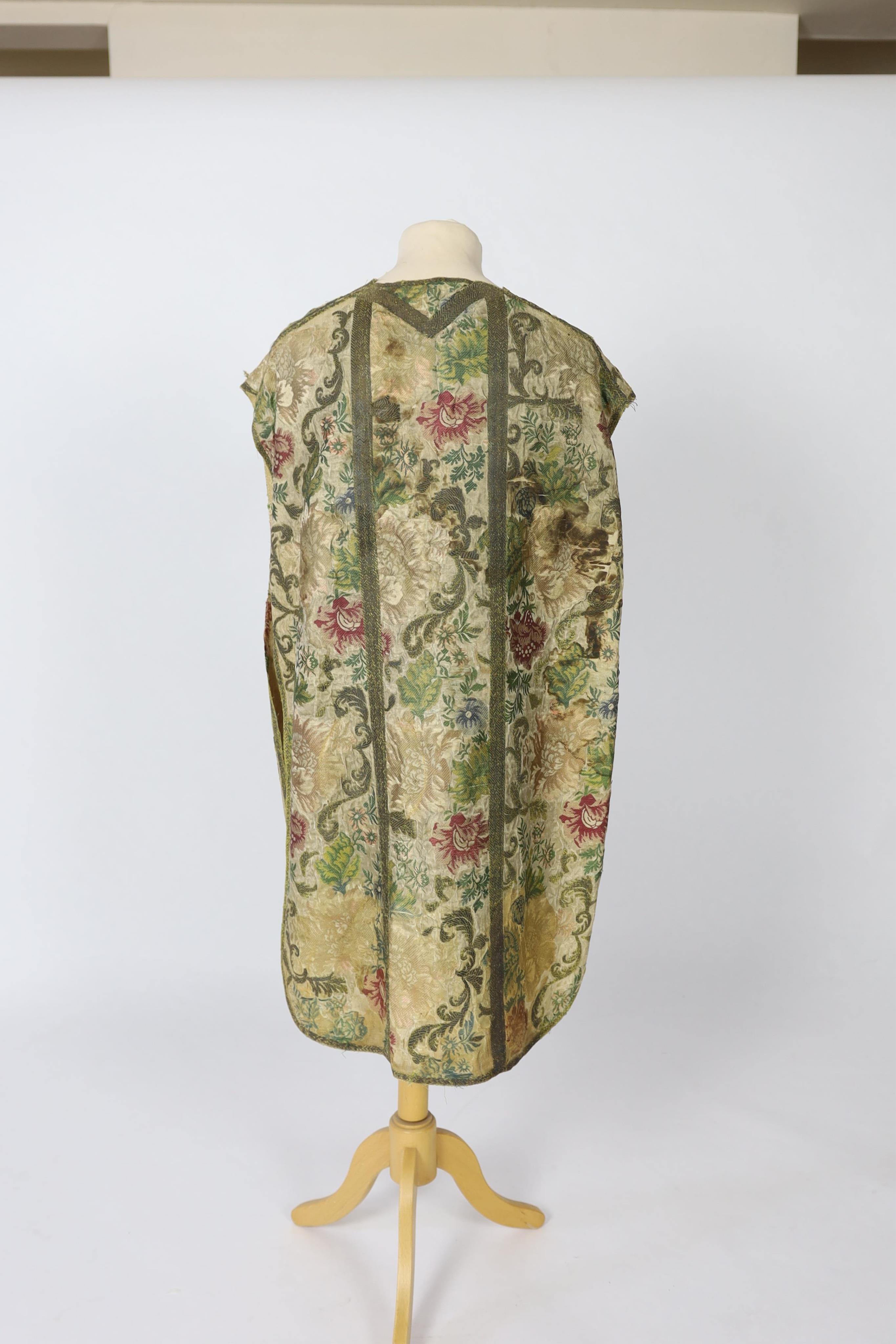 A late 18th century continental, possibly French, silk multi coloured and metallic brocade chasuble, lined with thick linen, edged and panelled with a thick metallic braid, 99cm long